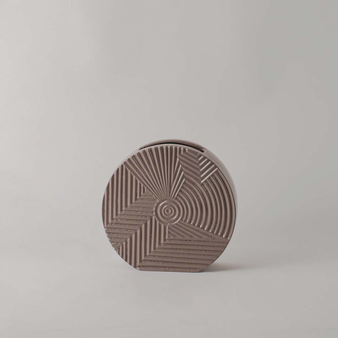 Matte brown round ceramic vase with etched geometric lines standing empty against a clean white background for display.