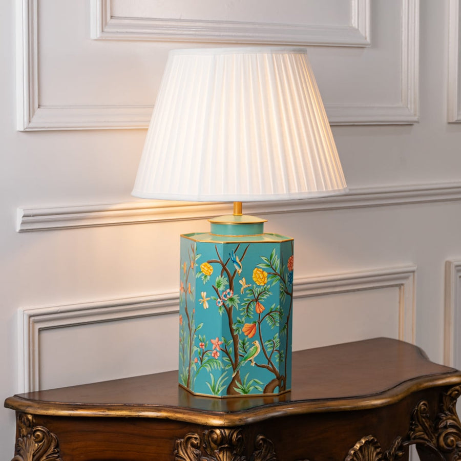 Table lamp showcasing white fabric shade with teal floral ceramic base and gold detailing styled on elegant wooden console.