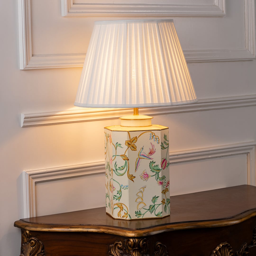 Table lamp on white background featuring pastel floral ceramic base with pleated fabric shade offering soft warm table lamping.