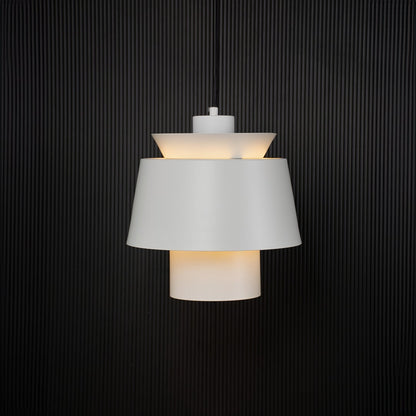A white pendant lamp glowing softly against a deep black background emphasizing its warm illumination and sleek contemporary silhouette.