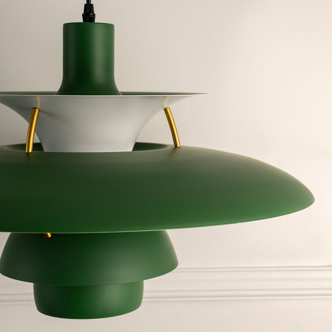 Closeup view of green metal pendant light showing layered shade construction and gold metal connectors with refined detailing.