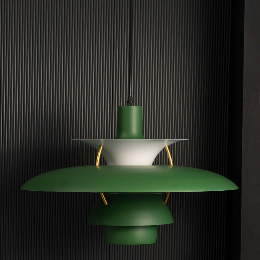 Green metal pendant light switched on against black background creating focused warm illumination for modern dining interiors.