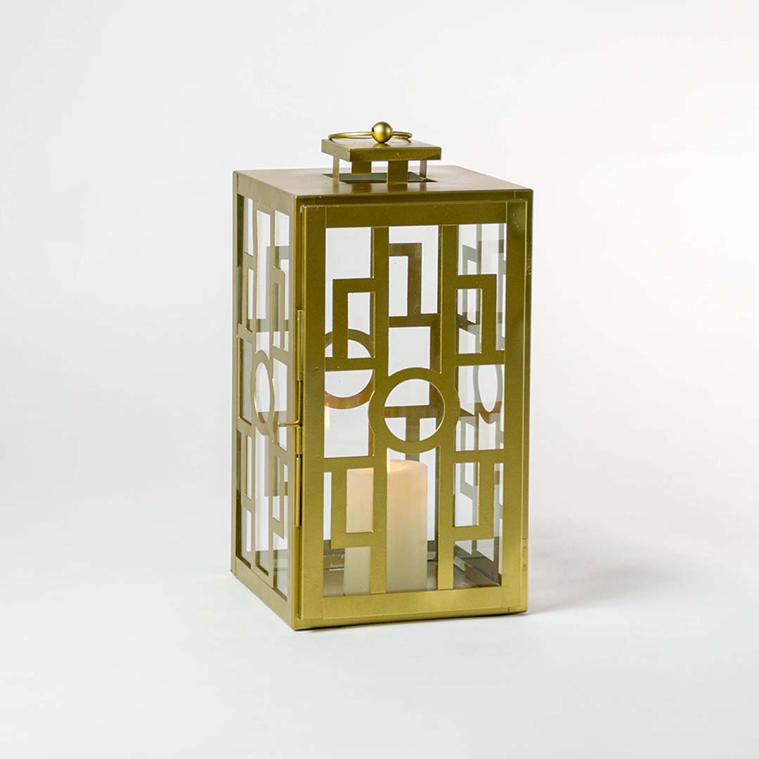 Gold metal lantern with geometric cutout panels and candle holder for luxury tabletop decor styling.