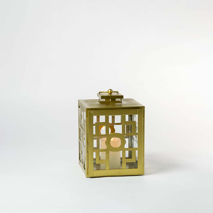 Gold metal lantern with geometric cutout pattern displayed on white background adding luxury accent to modern home decor.