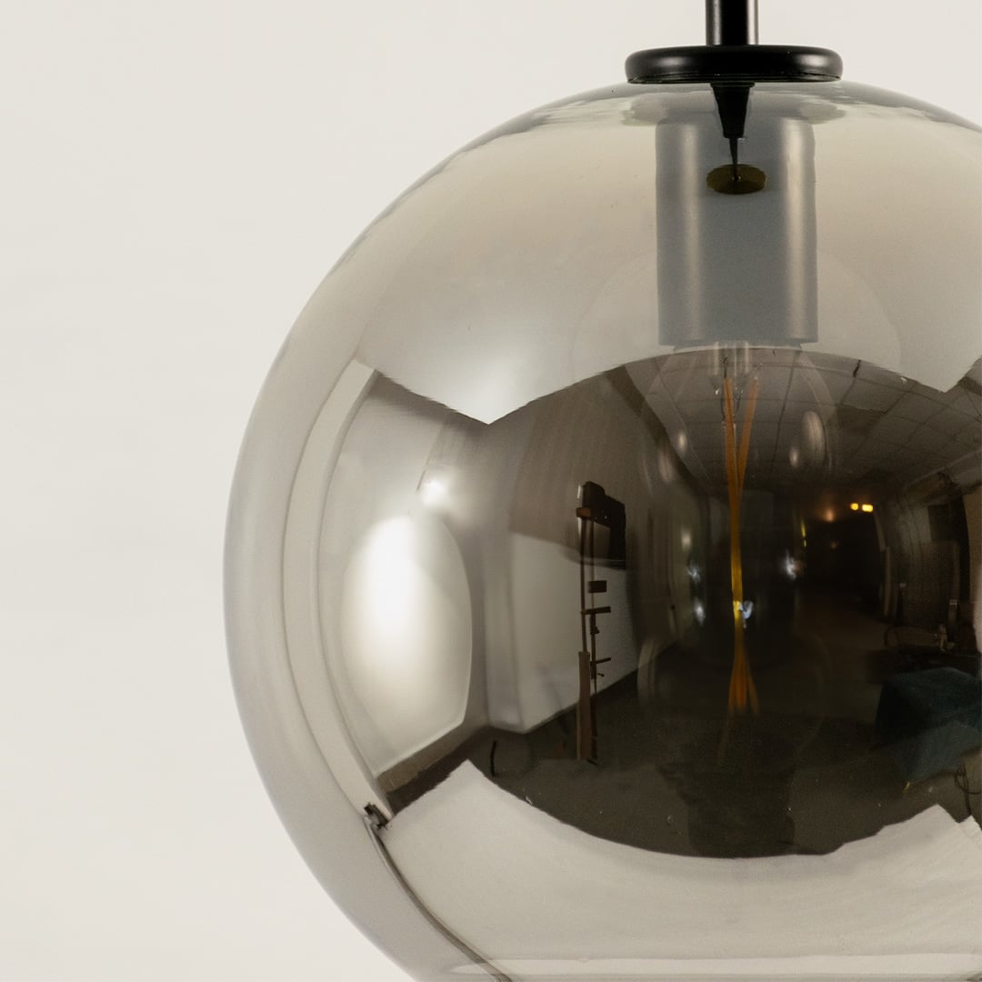 Closeup of smoked glass pendant light with globe design and black suspension rod stylish ceiling lamp for modern home interiors.