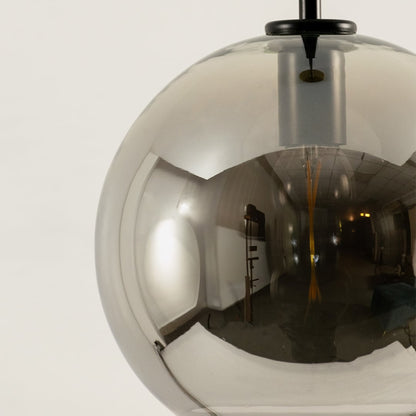 Closeup of smoked glass pendant light with globe design and black suspension rod stylish ceiling lamp for modern home interiors.