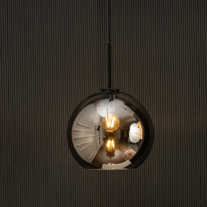 Smoked glass globe pendant light glowing on black background with warm filament bulbs creating moody modern interior lighting.