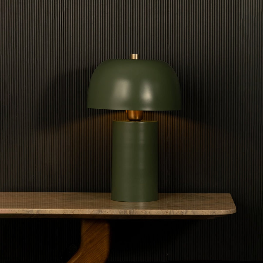 Green dome shade metal table lamp on wall shelf with light off and dark background for modern minimalist décor.