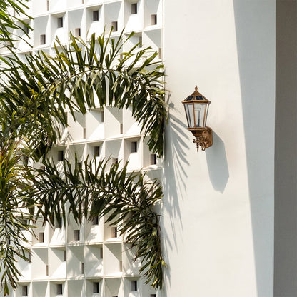 Outdoor antique gold wall lantern mounted on a light background showcasing its classic shape clear glass panels and elegant vintage design.