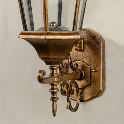 Close detailed view of the antique gold wall lantern showing the textured metal frame clear glass panels and ornate vintage styling.