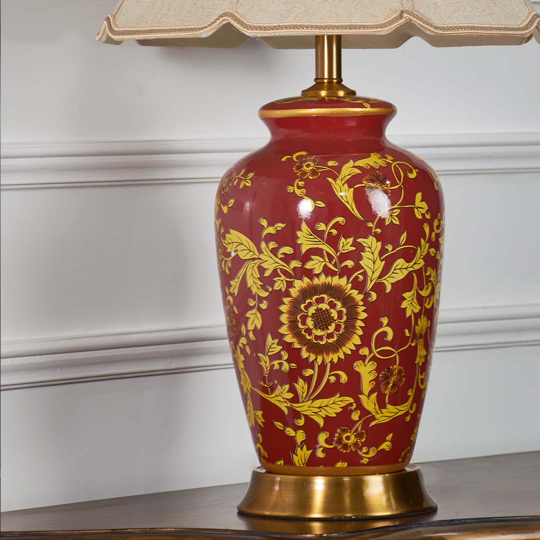 Red ceramic table lamp base showcasing intricate gold floral detailing and handcrafted artistry with a brass finish.