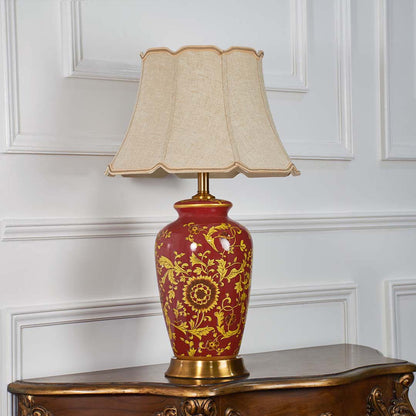 Traditional red and gold ceramic lamp turned off with ornate floral pattern and beige shade shown on a clean white background for timeless decor appeal.