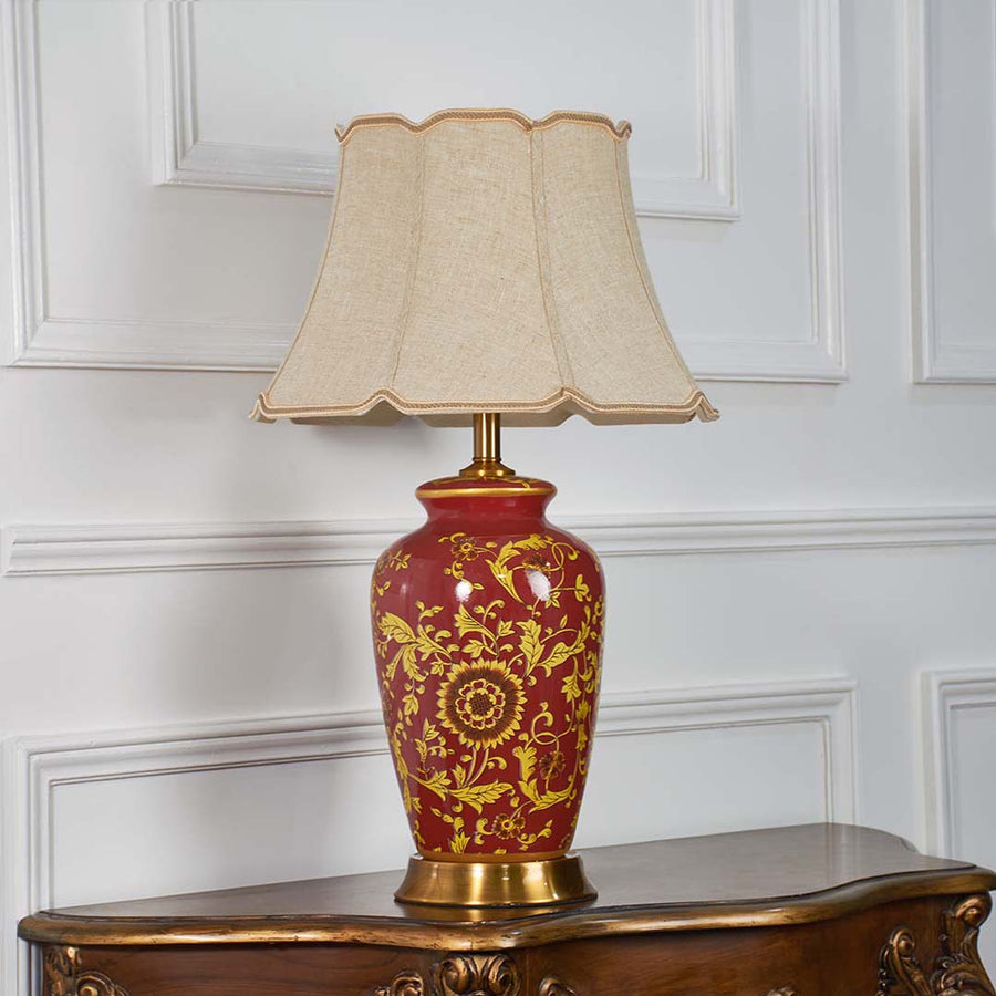 Traditional red and gold ceramic lamp turned off with ornate floral pattern and beige shade shown on a clean white background for timeless decor appeal.