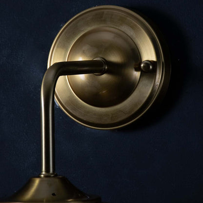 Detailed view of the gold wall sconce showing the clear teardrop glass shade and brushed metal finish highlighting craftsmanship and texture.