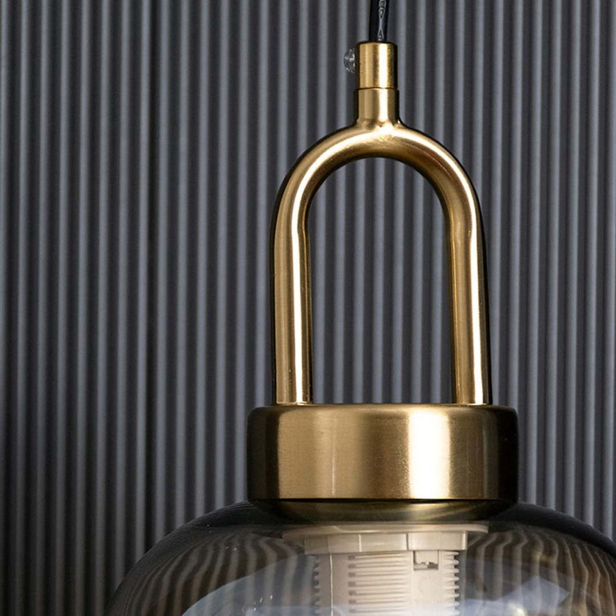 A detailed close view of the amber glass pendant light highlighting the curved tinted glass surface and gold loop accent suited for stylish decor.