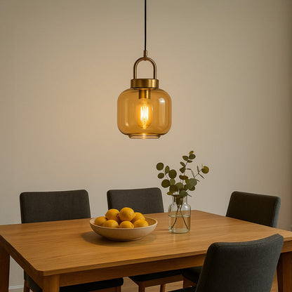 A modern gold and amber glass pendant light glowing warmly above a wooden dining table creating soft ambient lighting ideal for dining rooms and cozy interiors.