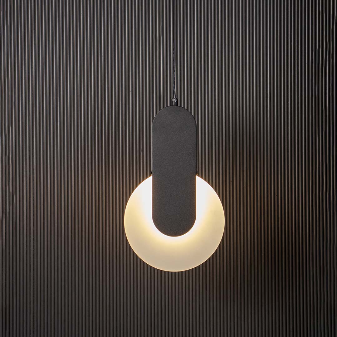 Geometric LED pendant light with black bar and white circular shade glowing on black background for home interiors/