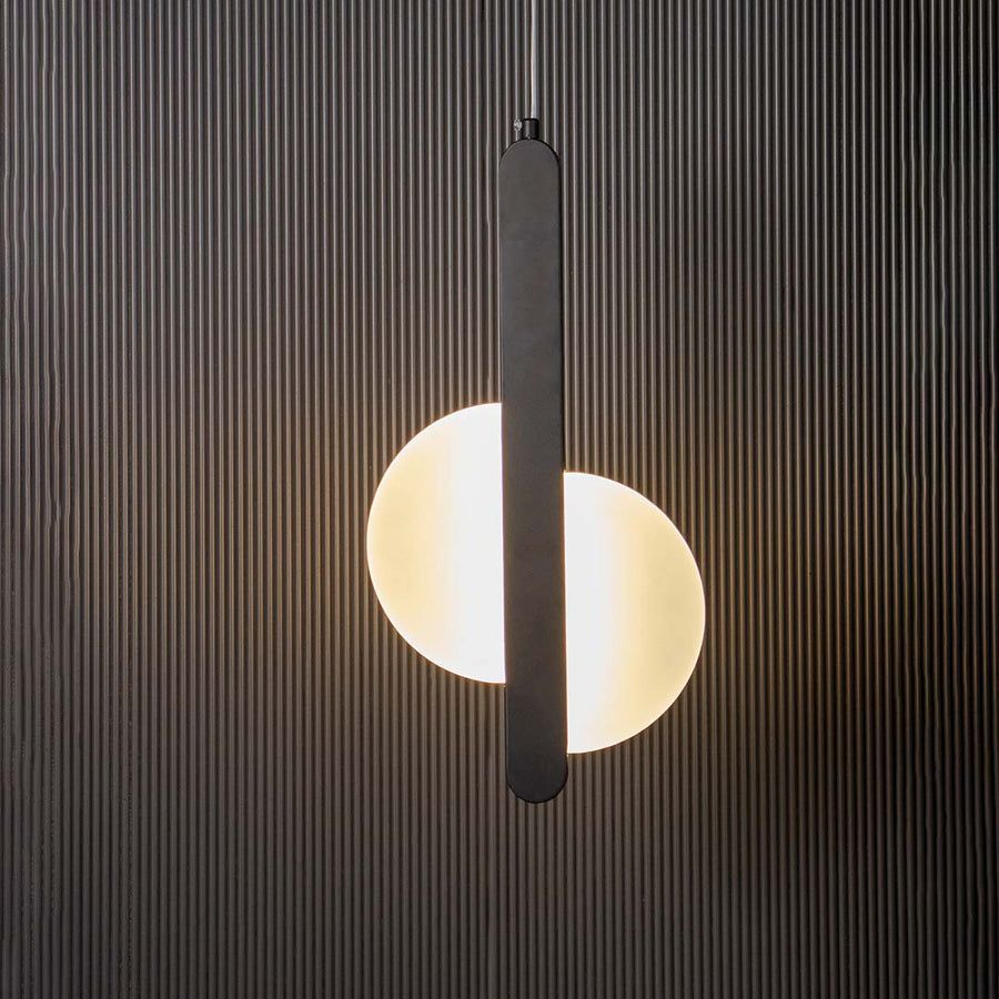 Modern black LED pendant light with vertical bar and frosted circular shade glowing on black background for interiors.