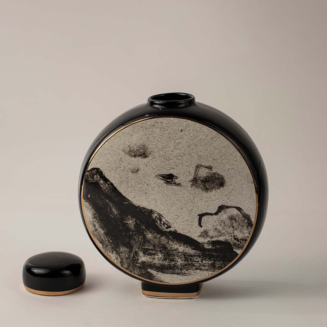 Stylish round black and beige ceramic vase with landscape motif captured on white background for home interior decor.