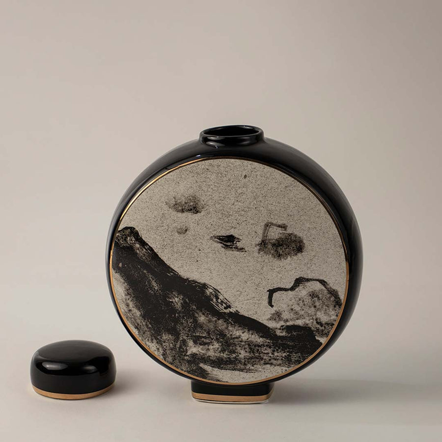 Stylish round black and beige ceramic vase with landscape motif captured on white background for home interior decor.