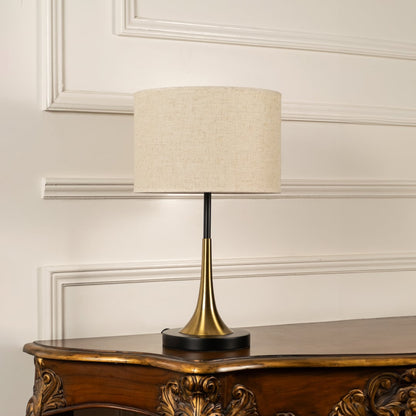 Halo glass table lamp with golden base and dome shade displayed on white background with light turned on for interiors.