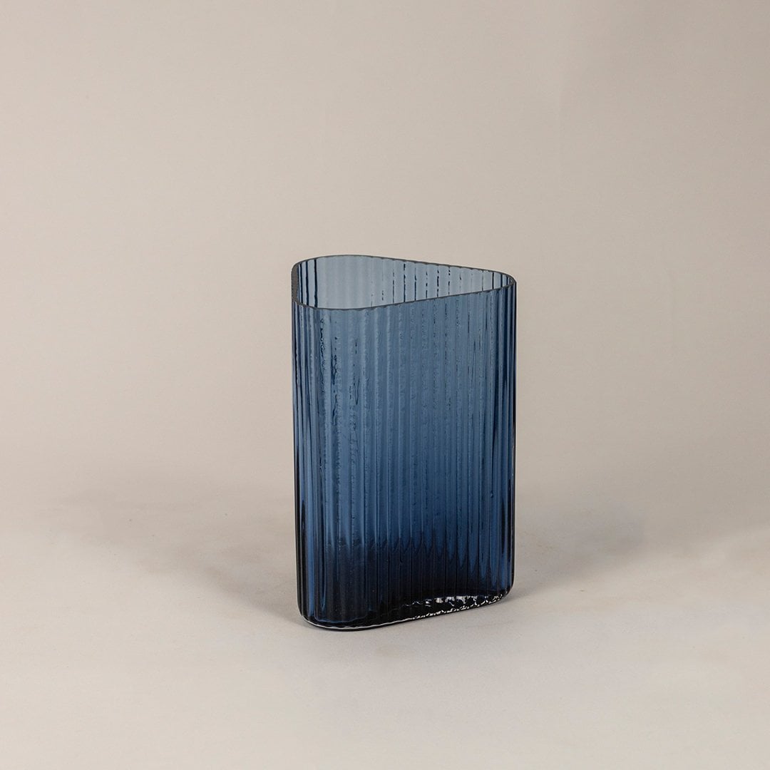 Side angle view of blue ribbed glass vase displaying vertical lines and smooth curved form for a stylish decorative accent.