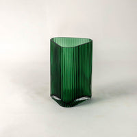 Green ribbed glass vase displayed on a white background featuring vertical grooves and a glossy finish for a modern minimal look.