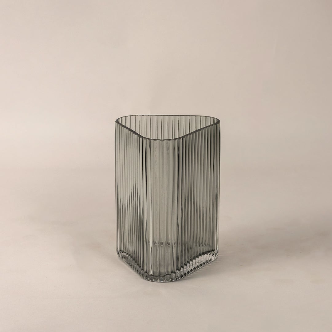 Side angle view of ribbed grey glass vase displaying curved top edge and fine linear pattern for an elegant decorative appeal.