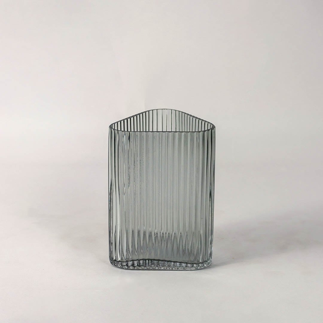 Textured grey glass vase with vertical grooves and rounded corners placed on plain white surface for a clean modern presentation.