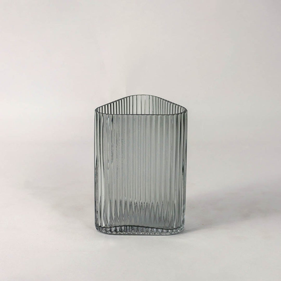 Textured grey glass vase with vertical grooves and rounded corners placed on plain white surface for a clean modern presentation.