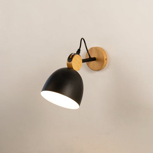 Nordic style matte black and natural wood dome wall sconce turned on against a plain off white background surface.