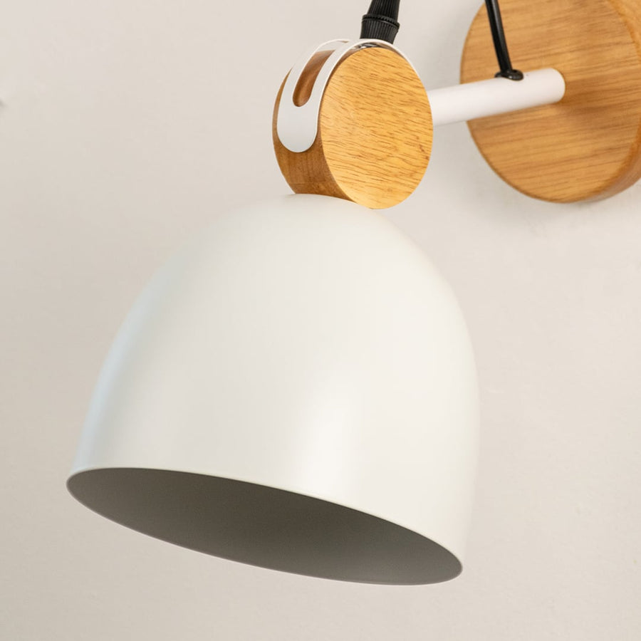 Detailed macro shot of a white dome wall lamp focusing on the natural wood swivel hinge assembly and metal mount bracket.
