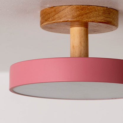 Closeup view of the ceiling light showing the natural wood texture and smooth pink shade with a neat modern finish.