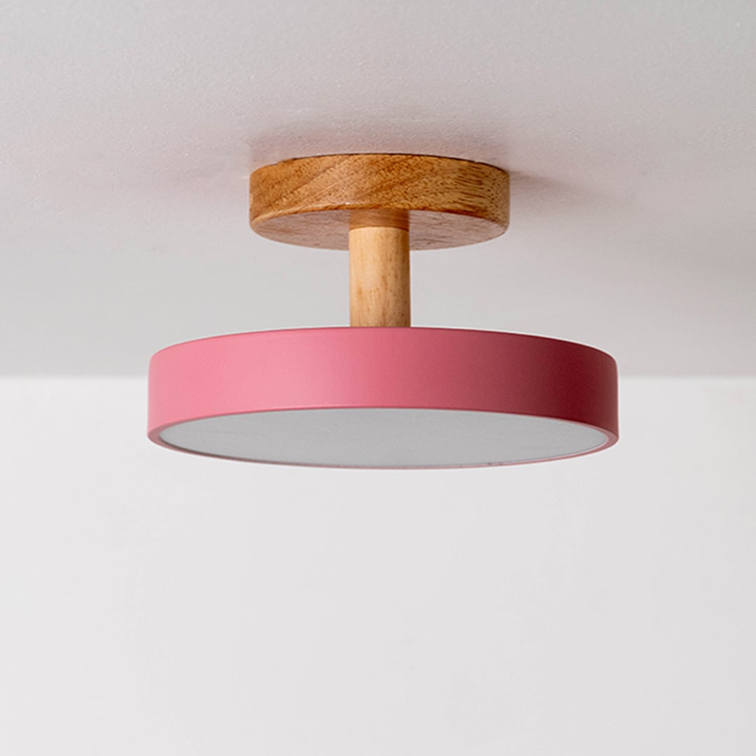 Ceiling light displayed off on a plain white background highlighting the wooden mount and pink shade in a minimal modern design.