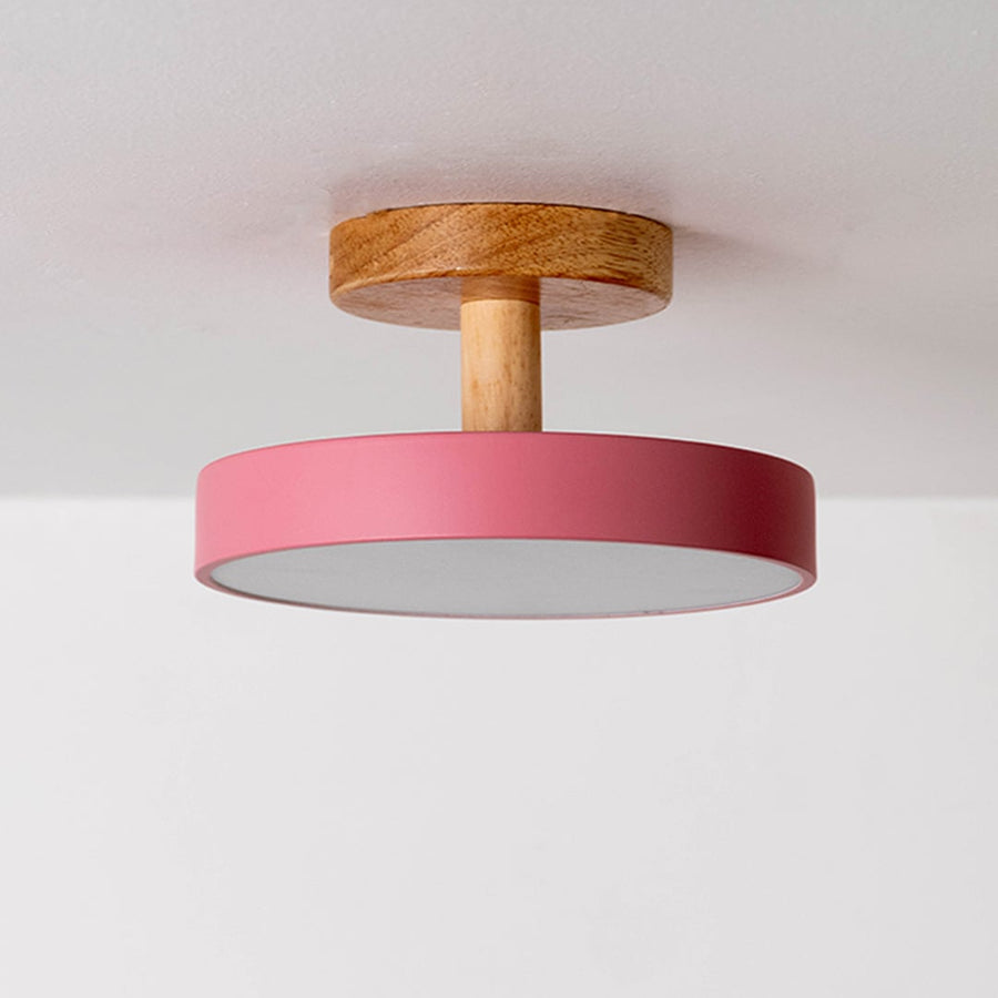Ceiling light displayed off on a plain white background highlighting the wooden mount and pink shade in a minimal modern design.