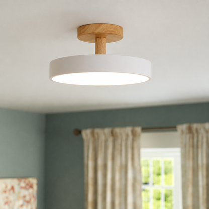 A modern semi-flush ceiling light with a white cylindrical shade and a natural oak wood ceiling mount, shown illuminated in a room setting with a window and curtains in the background.
