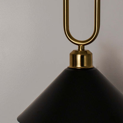 Closeup of black metal pendant light with polished gold loop detailing and refined finish.