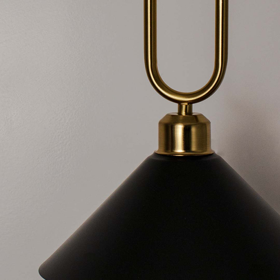 Closeup of black metal pendant light with polished gold loop detailing and refined finish.