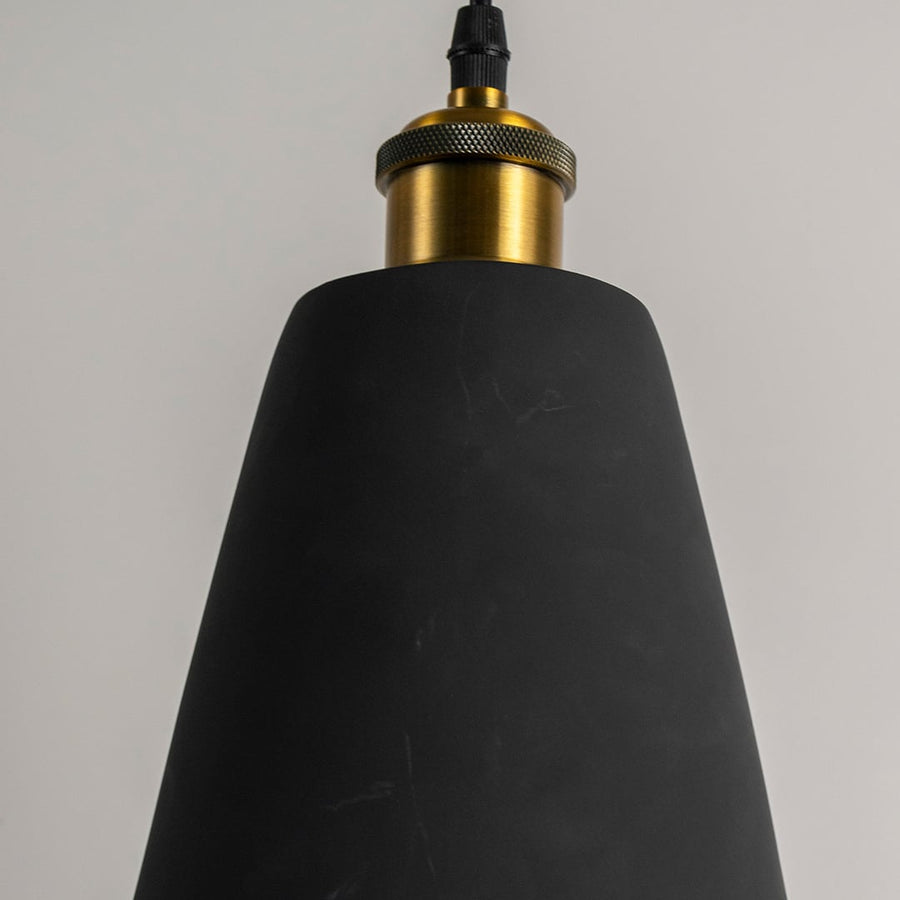 Closeup of black cone pendant light turned off showing smooth matte finish and detailed brass top for modern lighting design.