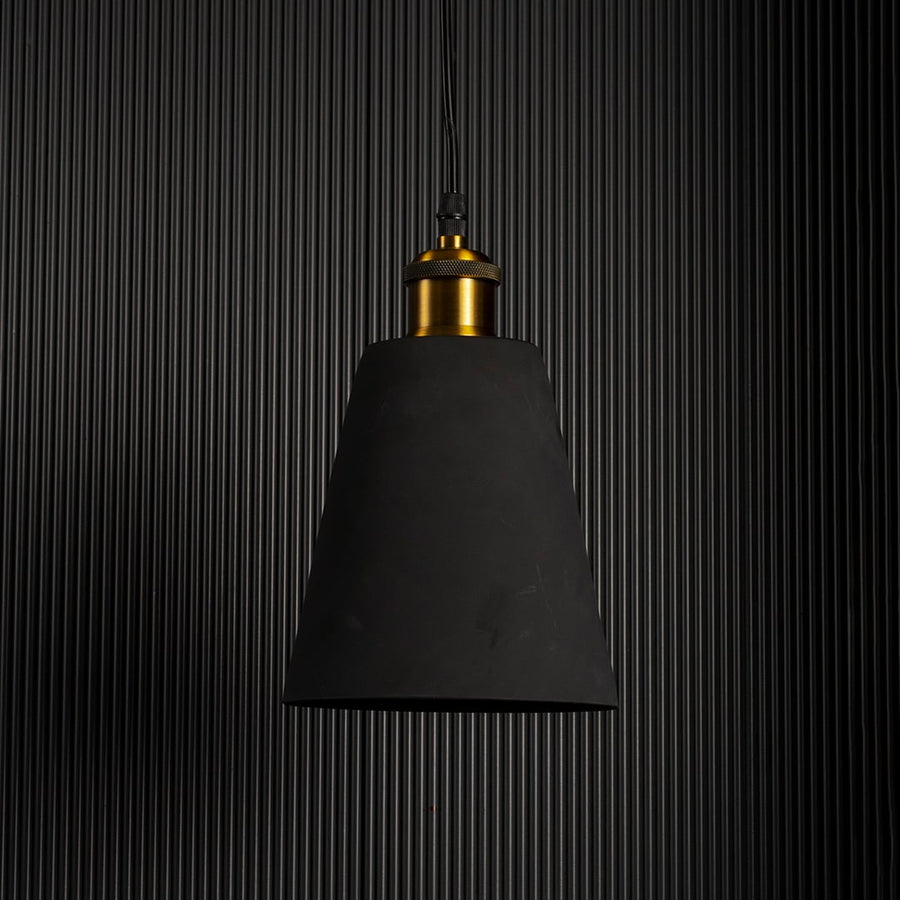 Black cone pendant light turned off with brass fitting visible against black background emphasizing sleek industrial style.