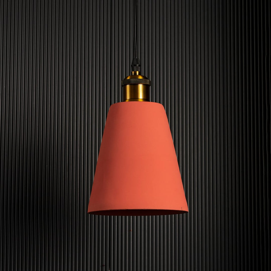 Terracotta cone pendant lamp turned off against a dark background emphasizing its elegant color and warm lighting.