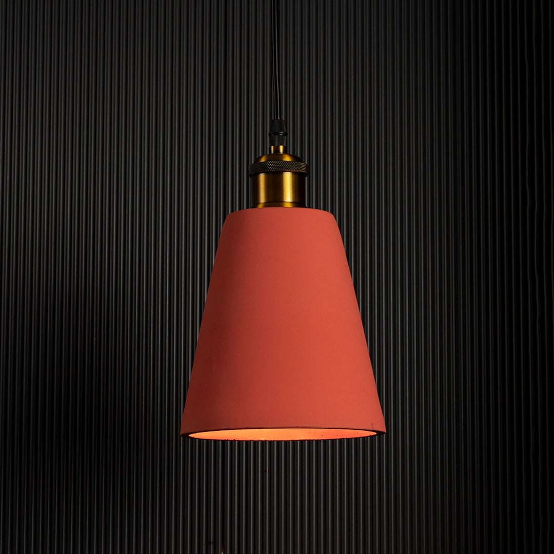 Terracotta cone pendant lamp glowing against a dark background emphasizing its elegant color and warm lighting.