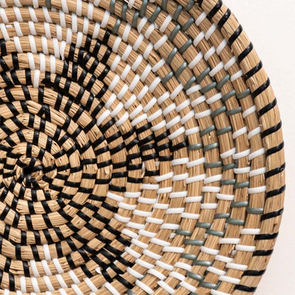 Closeup of woven wall basket featuring mixed beige and black fibers with dynamic pattern highlighting handmade decor detailing.