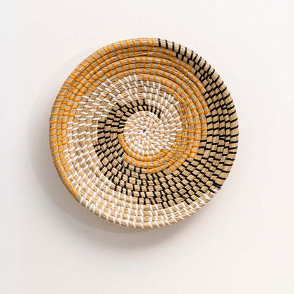 Amber and natural woven decorative wall basket with spiral pattern for elegant wall styling and contemporary home decor.