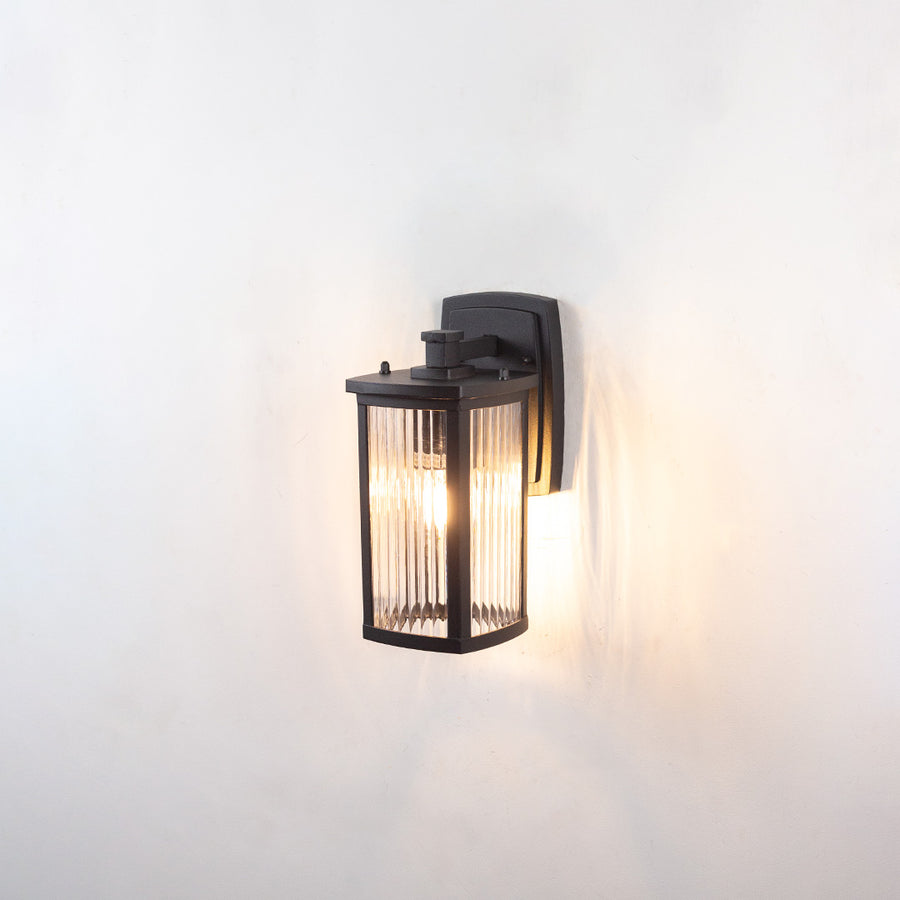 Black metal outdoor wall light dimension image with ribbed clear glass shade and warm internal bulb for patio decor.