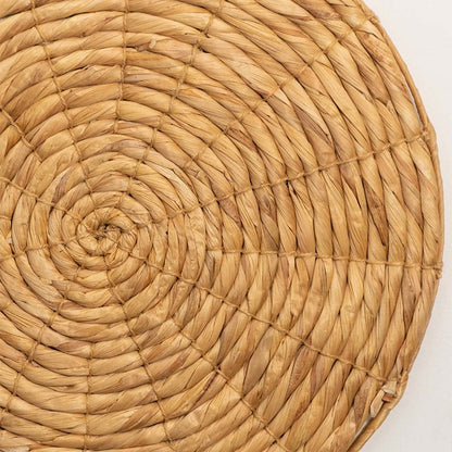 Closeup view of handwoven natural fiber round wall decor showing detailed spiral weave texture and warm earthy tones on a clean white background.