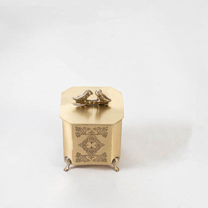 Gold vintage-style metal box placed on white background highlighting engraved details and bird handle.