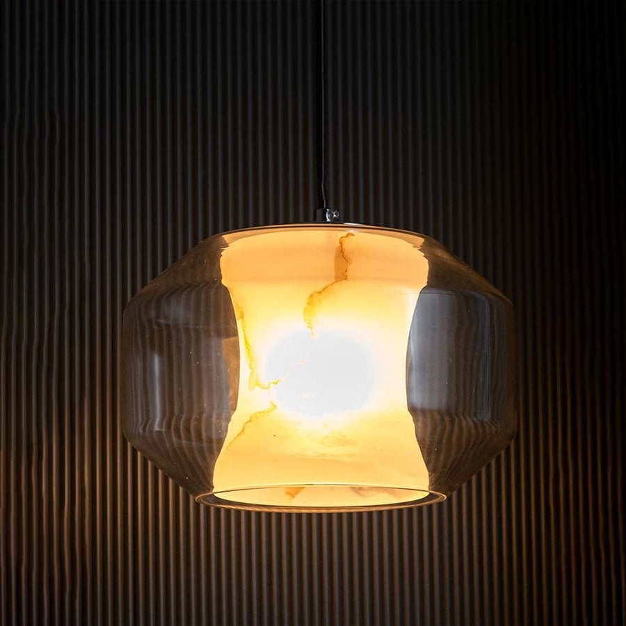 A pendant light with its warm light on placed against a dark black background creating a striking contrast that accentuates its glossy form and soft glow.