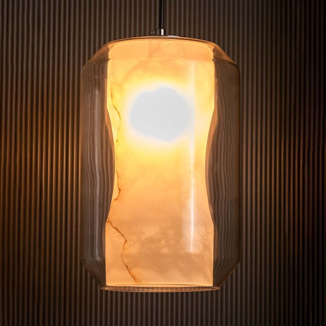 A glowing marble cylindrical pendant light with warm illumination against a black background enhancing its frosted white marble texture and modern style.