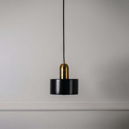 Black and gold pendant ceiling light with sleek cylindrical shape presented against minimal off white background for decor.